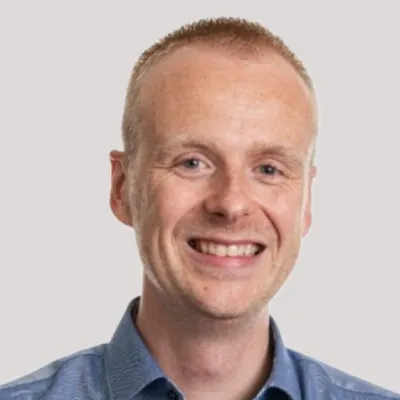 Jidde standing with folded hand and smiling at the camera